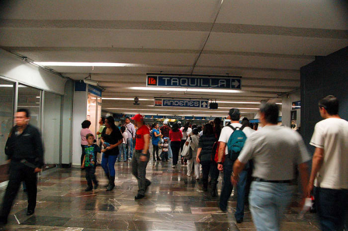 Look at the first blue sign. It says "taquilla" the Spanish word for ticket booth. The other word "Andenes" lets you know the direction in which the tracks are.