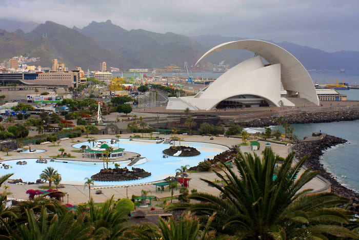 The mountains of Anaga, the Parque Maritimo Cesar Manrique and the distinctive architecture of the Tenerife Auditorium, with Palmetum palms in the foreground