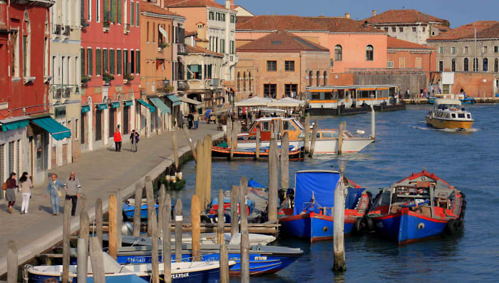 The pavements of Murano are lined with cafes and restaurants, souvenir shops and - of course - numerous ornamental glass retail outlets. This waterway is the Canale Ponte Lungo. In the distance is the vaporetto water bus station of Murano Museo
