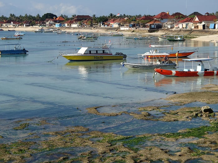 The sea slowly recedes during afternoon low tide, leaving boats sitting in a few inches of water.