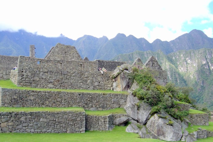 View of a young couple relaxing and enjoying the serenity of Machu Picchu's walls and terraces after a day of touring. The Andes are in the background.
