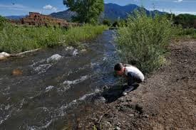 Red Willow River (drinking water on the pueblo) with pueblo and Taos mountains in the background.