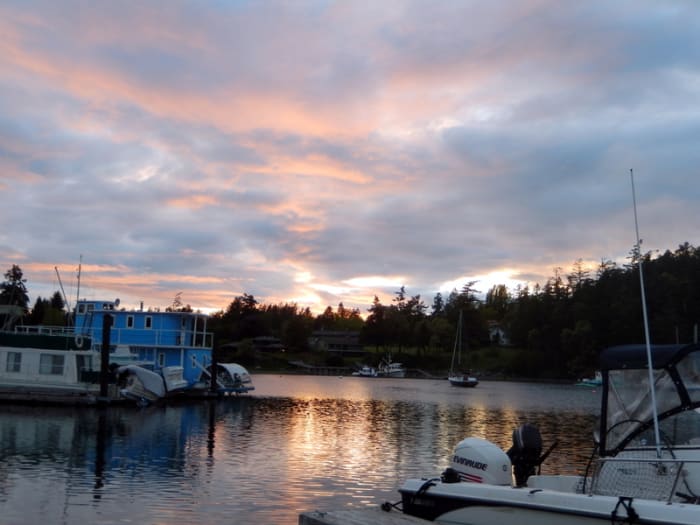Striking colors cloak a small, tranquil side bay cradling a few small houseboats and fishing boats as the forest ashore welcomes the setting sun.