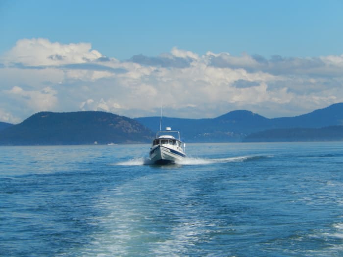 A C-Dory, a small pocket cruiser, crossing Rosario Strait, with some of the San Juan Islands in the background.