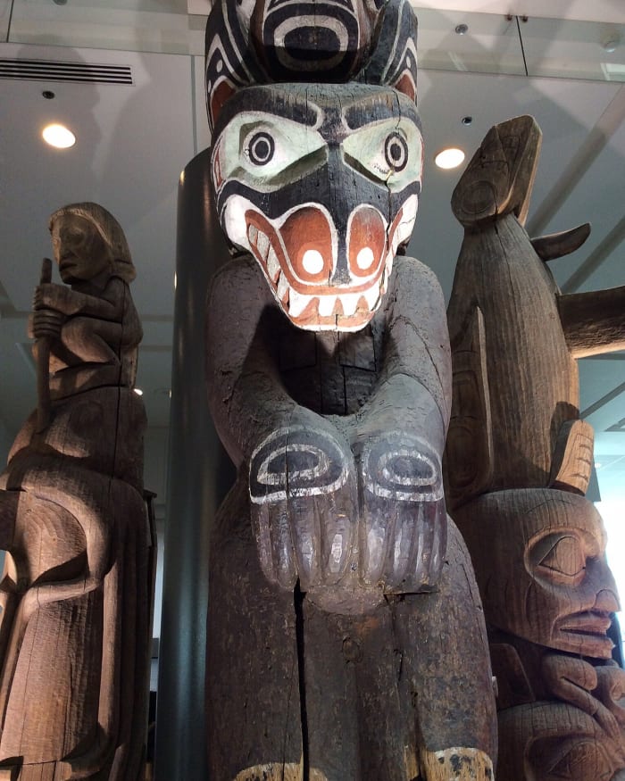 This is a close-up view of the three totem poles in the Vancouver Convention Centre. The middle pole is very tall and extends to the second storey of the building.