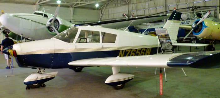 1964 Piper Cherokee 180 (im Vordergrund) wird im 1940 Air Terminal Museum Hangar versteigert