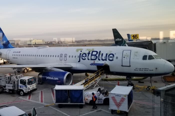 This JetBlue plane has seen better days. Some paint issues are visible near the front of the aircraft and around the JetBlue logo.