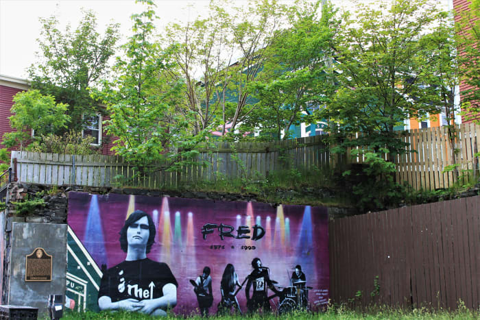 Mural of Fred Gamberg, painted in his memory, on a concrete wall on the corner of Duckworth and Prescott Streets in Downtown St. John's. The LSPU Hall can be seen in the background.