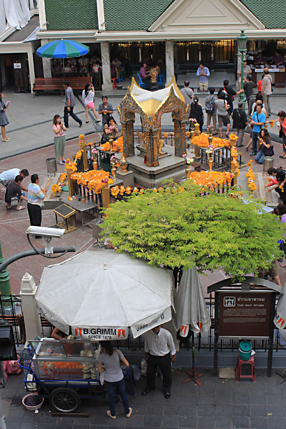 The shrine in the forecourt of the Grand Erawan Hotel, with street vendors in the foreground and the hotel entrance behind