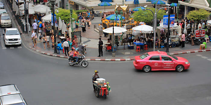 The ancient religious traditions of the Erawan Shrine top of picture, and the busy traffic of the 21st century metropolis in the forground