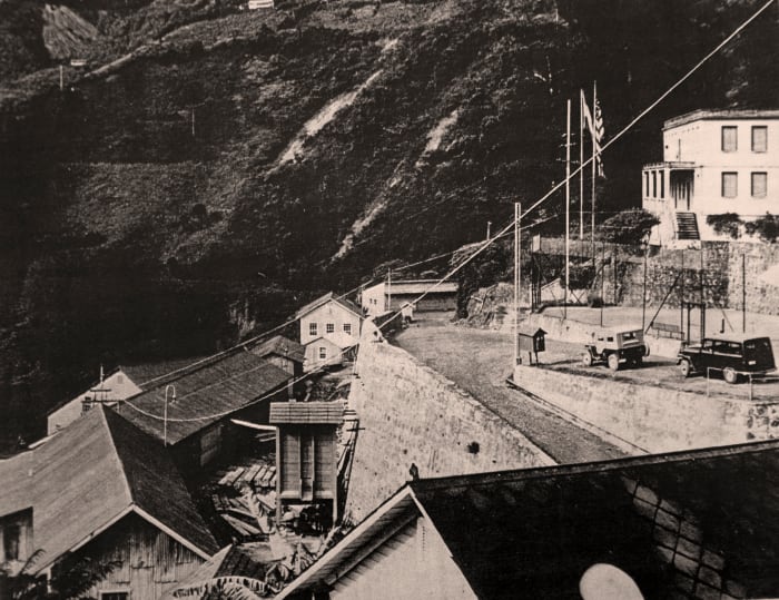 View to left of mill site, showing US Consulate at upper right, with flags.