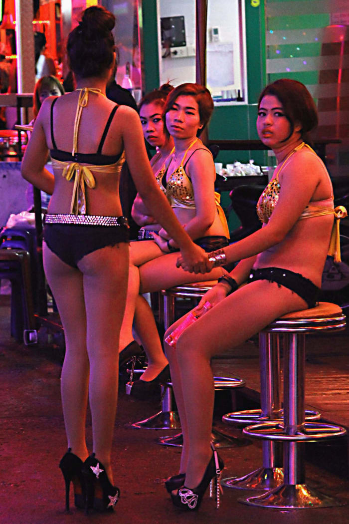 Bar girls at Soi Cowboy. Here a string of neon-lit clubs - many of which present revealing shows - will have scantily dressed girls on the street to draw the customers in for shows or drinks - or to ply whatever other business they may have in mind