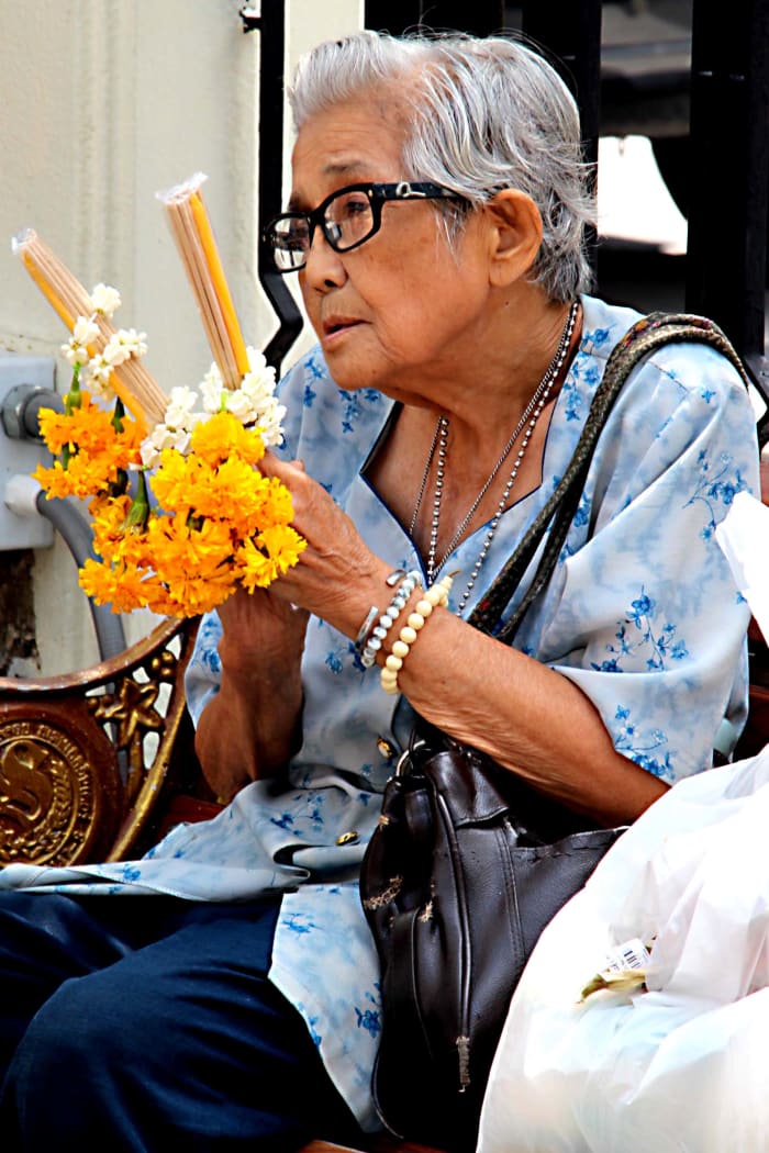 An elderly woman makes offerings at the Erawan Shrine - site of a terrorist bombing just one month before this photo was taken, but soon restored to its status as a hugely popular site of devotion and prayer for shoppers and workers in the city.
