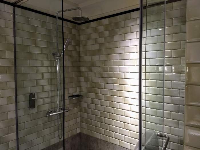 Shower stall to the right with a rain showerhead and hand-held shower.