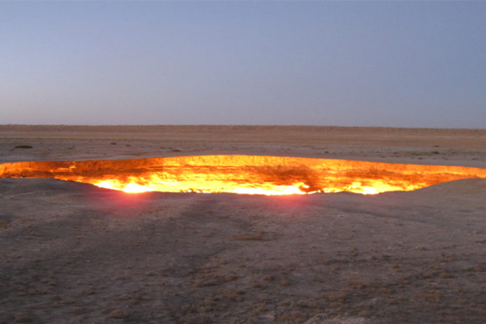 A fiery doorway to Hell that burns amid a barren desert landscape.