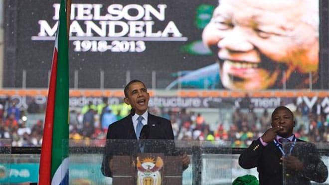 Fake Signifier and Signaler: President Barack Obama waves standing next to the sign language interpreter after making his speech at the memorial service for former South African president Nelson Mandela at the FNB Stadium in Soweto near Johannesburg,