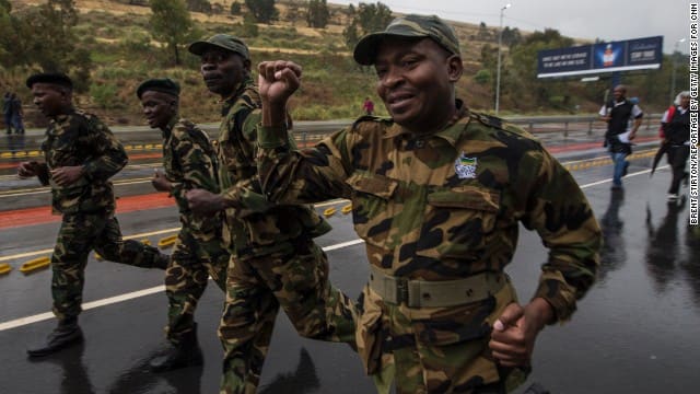 Former members of the armed wing of the African National Congress run through the streets on their way to the memorial service.