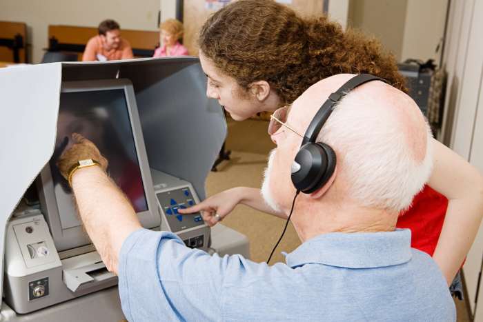 A poll worker shows a voter how to use an accessible voting machine. Image © Can Stock Photo Inc. / lisafx.