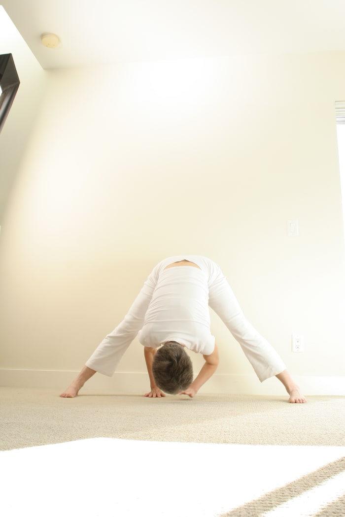 Wide Legged Forward fold yoga pose for hip opening stretches the adductors inside the thighs, the gluteals in the buttocks, the hamstrings, and the muscles of the lower back.