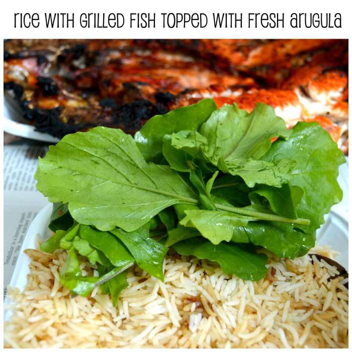 A delicious meal of flavoured rice and grilled fish, served with a topping of fresh crisp arugula leaves.