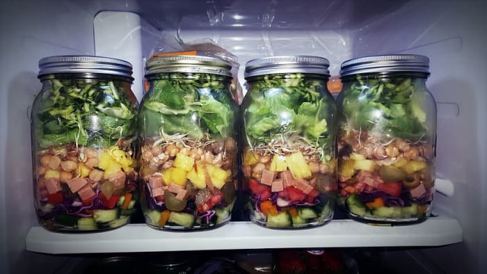 The trick is to put firmer vegetables on the bottom-- they can marinate in a little dressing. Add leafy greens on the top, above the dressing so they won't wilt. Dump in a bowl when ready to eat, to mix the dressing and ingredients.