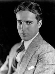 black and white portrait of Charlie Chaplin in his youth dress in a white shirt tie and suit coat circa 1920 publicity photo