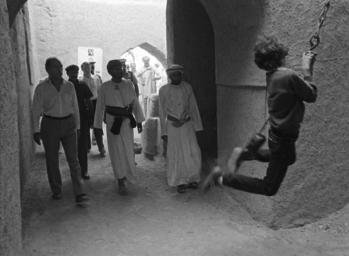 Pierre Trudeau, left, watches as his 11-year-old son Justin swings on a chain during a tour of an old fort in the Omani town of Nizwa (Dec 2, 1983).