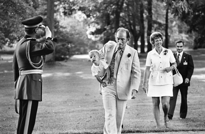 PM Trudeau arrives at a Garden Party at Government House with Justin under his arm, as an RCMP salutes (Aug 1973).
