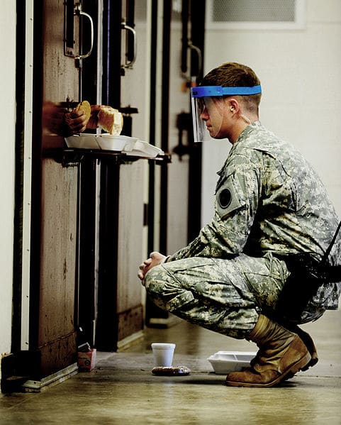 Meal time at Guantanamo Bay. Guards wear masks because sometimes urine or feces will come flying out of the food portal.
