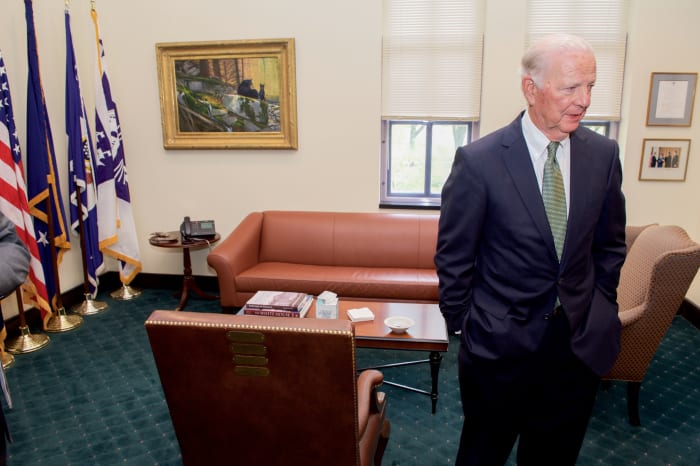Former U.S. Secretary of State James A. Baker III stands by the chair he used as a Cabinet officer - lined with brass plates for each office he held - after he welcomed U.S. Secretary of State John Kerry to his private office on April 26, 2016.