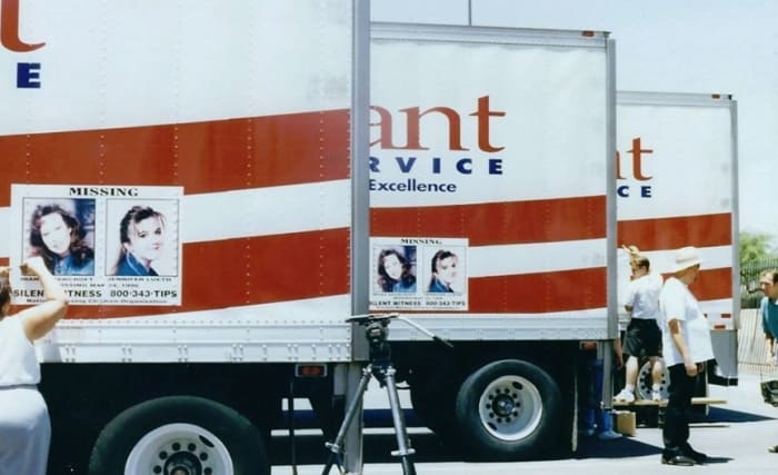 Staff at the National Center for Missing Adults applying full size color posters on local trucks from Alliant Food Service.