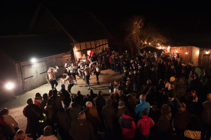 Crowds look on as the Morris Men make merry outside the barn.