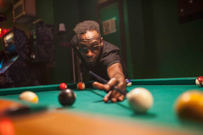 Professional African-American billiards player "Jeremiah Karne" lining up his classic "Akachi God's hand Billiards Shot" in the Mens Man-Cave Cue Sports Semifinals