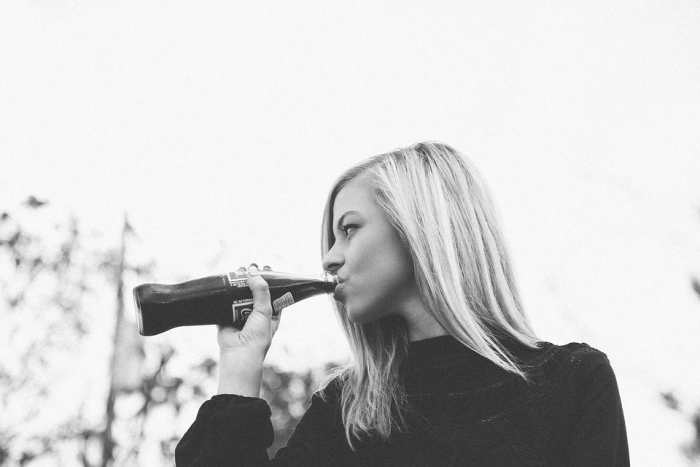 Notice: this pretty girl is enjoying A Soft Drink in a bottle that the brand is NOT noticeable.
