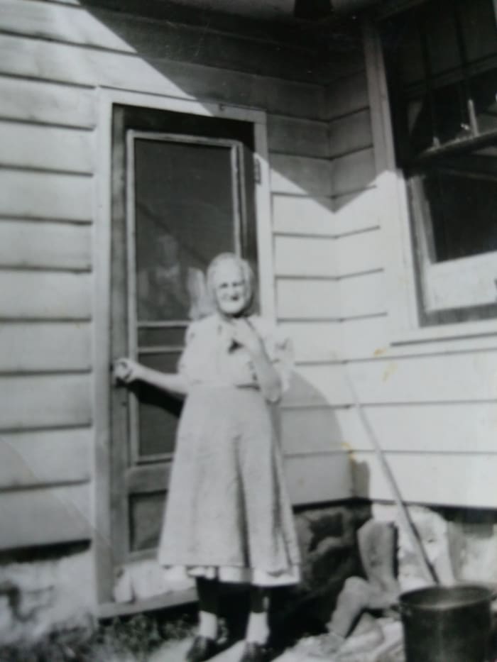 My little grandma outside of her home in probably the early 50s. The man behind the screen door is probably great-uncle John.