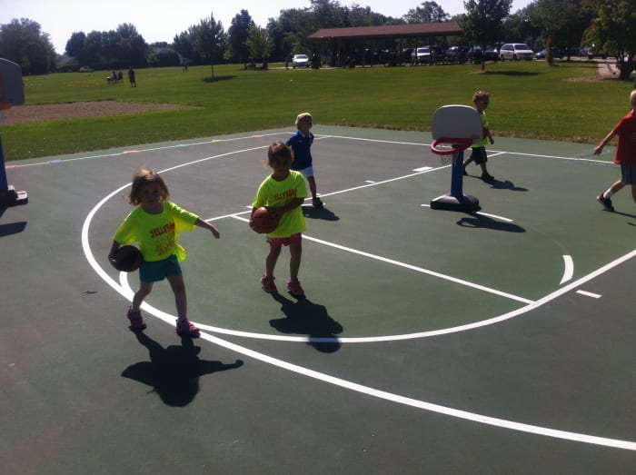 Young children walk with basketball on their pockets shielding the ball with other arm