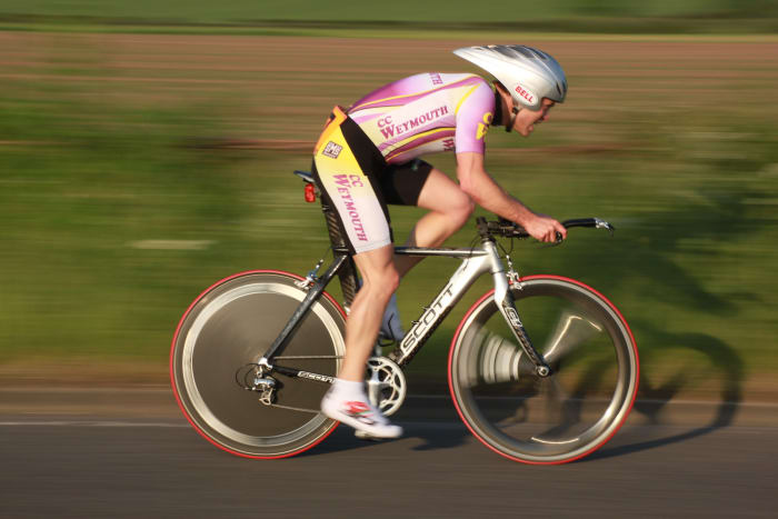 An erodynamic helmet, time trial bicycle, and aerodynamic wheelset with a rear disc can help you ride a faster time trial. Bike pictured is a Scott Plasma with a fron HED tri-spoke carbon wheel and disc wheel to cut through the air