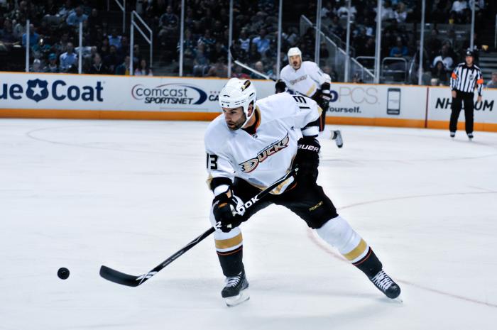 A hockey player is skating on ice while holding a hockey stick. He is going for the puck.
