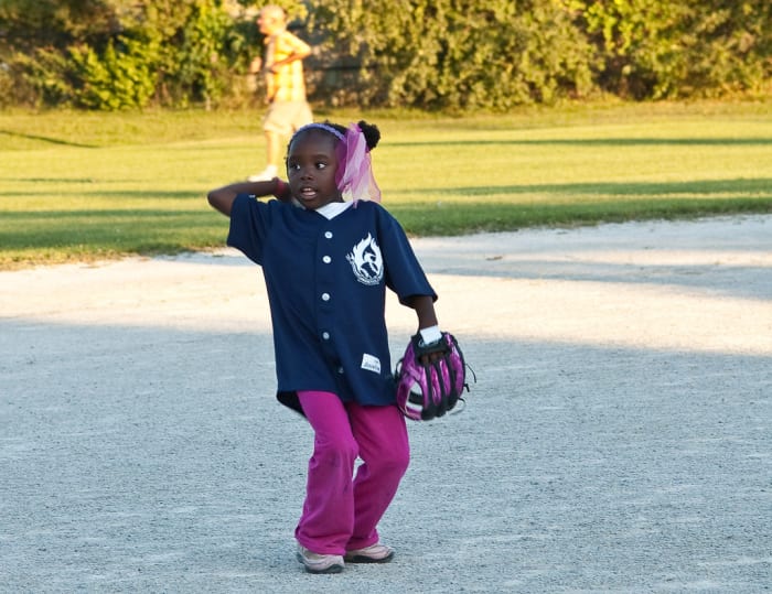 A little girl throwing a ball.