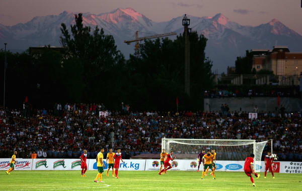 Azamat Baimatov (#7, red) attempts a shot during a 2018 FIFA World Cup qualifier between Kyrgyzstan and Australia on June 15, 2015 at Dolen Omurzakov Stadium in Bishkek, Kyrgyzstan