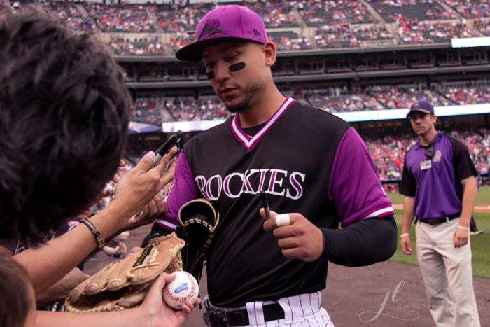 Former Colorado Rockies outfielder Carlos Gonzalez signs an autograph for a fan during the 2018 season.