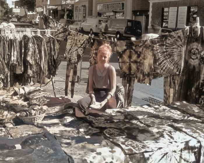 The AI had no idea what color to make this vendor's colorful tie-dyed apparel, so it gave up entirely.