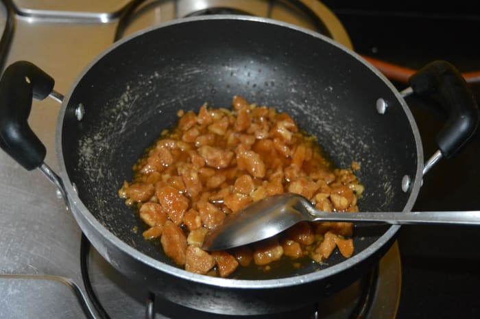 Step three: Heat a deep bottomed pan. Add powdered jaggery and 2 tablespoons of water. Stir the mixture. After some time, jaggery melts completely.