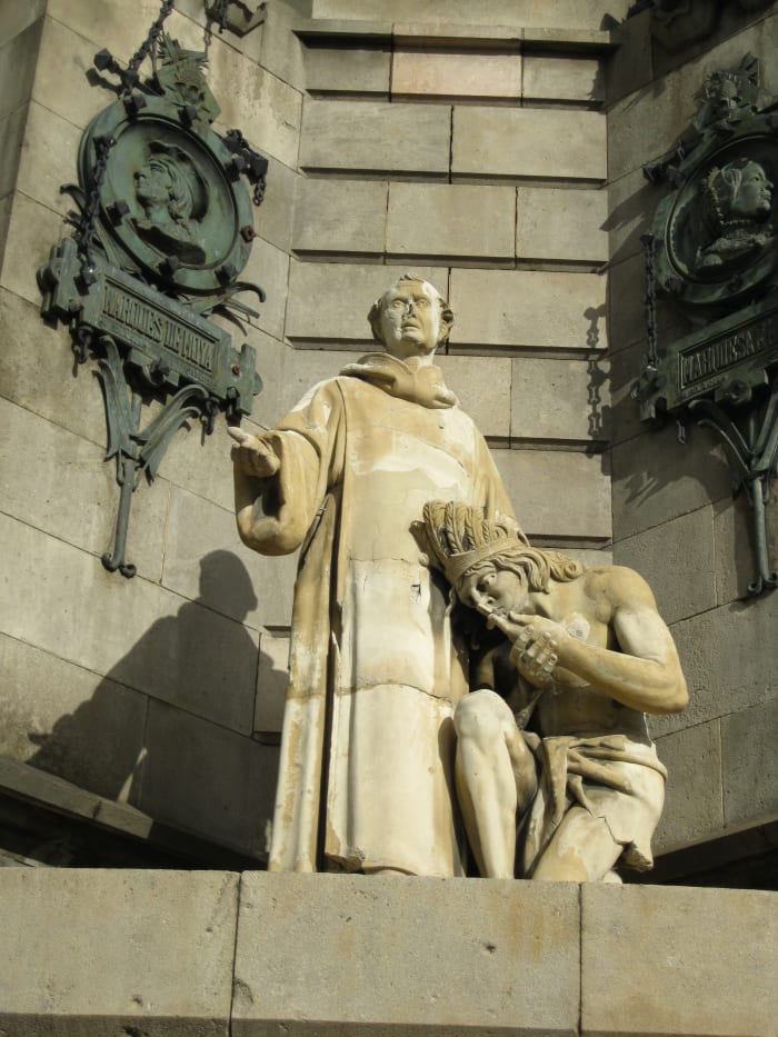 Priest with a kneeling Indian at base of Columbus Monument in Barcelona, Spain