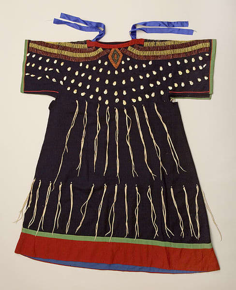Often found in Idaho, the wing dress came from the tail dress or two hides dress. The T-shaped yoke extends into cape-like sleeves. A printed cotton shirt or skirt was worn under the wing dress.