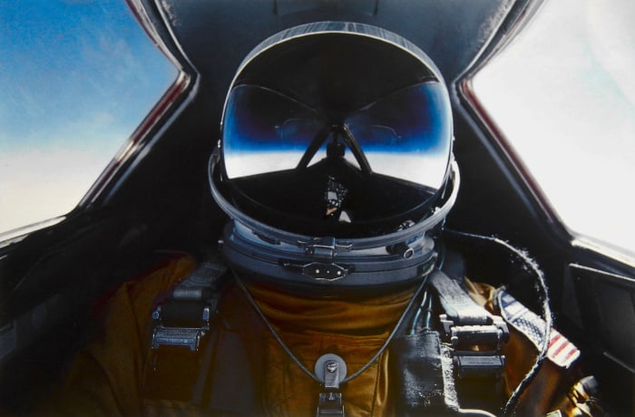 A SR-71 pilot in his pressurized suit whose helmet's visor captures the inky blackness of near space as the plane reached altitudes of over 80,000.