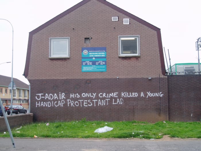 Anti-Johnny Adair graffiti in the UDA Lower Shankill, Belfast, after he was expelled in an intra-UDA feud.(Presumably if the disabled kid had been Catholic that would not have been seen as problematic?)