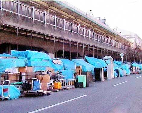 Homeless in Osaka, Japan. There are about 25,000 people homeless in Osaka. The entrance of the area's largest shelter, with 20-foot pale green metal walls dominating the park
