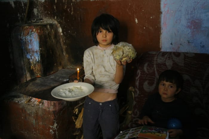 Small boy in poverty asking for food. Wearing dirty clothes as if he has not showered for several days.