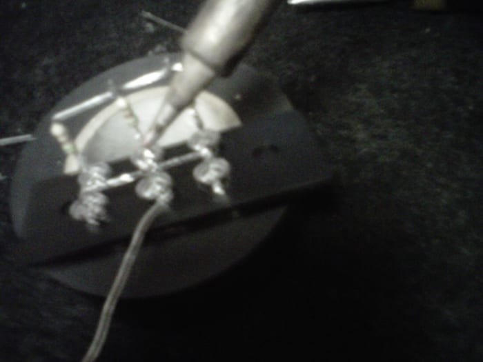 Soldering the lead across the - side. See that the + side (with resistors) is already done.